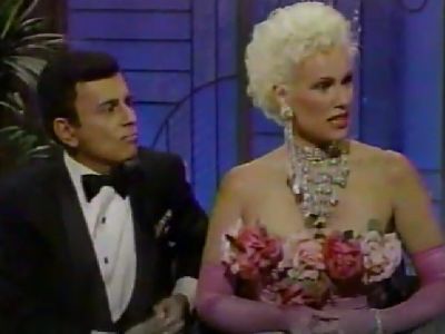 Casey Kasem is on a tuxedo whereas, Jean Kasem is wearing a pink dress with flowers on it.